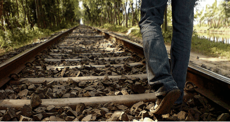 photo of person walking along railroad tracks